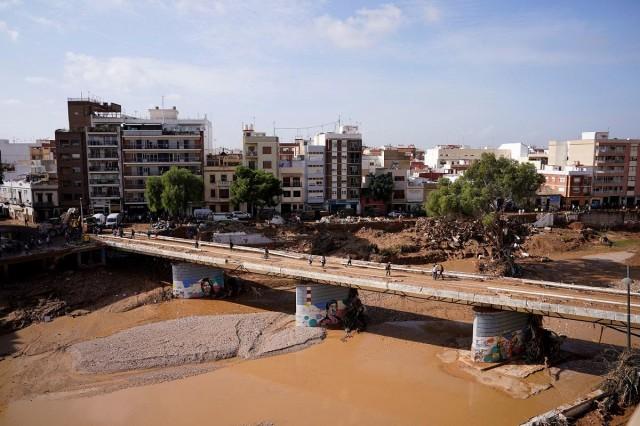 People cross a bridge affected by heavy rains in Paiporta, near Valencia, Spain, November 5, 2024. REUTERS/ Ana Beltran