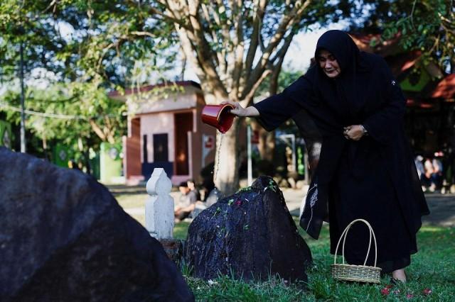 A Muslim woman pours water while visiting Ulee Lheue mass grave, where victims of the 2004 Indian Ocean tsunami are buried, during the 20th anniversary in Banda Aceh, Aceh, Indonesia, December 26, 2024. REUTERS/ Willy Kurniawan