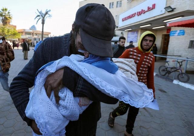 Yahya Al-Batran, the father of Palestinian infant Jumaa Al-Batran, who died of hypothermia after living in a tent with his displaced family, embraces his body at Al-Aqsa Martyrs Hospital, in Deir Al-Balah in the central Gaza Strip, December 29, 2024. REUTERS/ Ramadan Abed