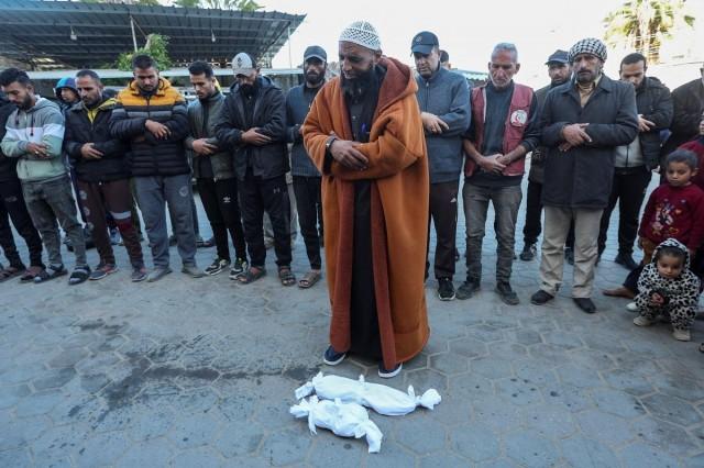 People pray next to the bodies of two Palestinian babies, including infant Jumaa Al-Batran, who died of hypothermia after living in a tent with his displaced family, at Al-Aqsa Martyrs Hospital in Deir Al-Balah in the central Gaza Strip, December 29, 2024. REUTERS/ Ramadan Abed