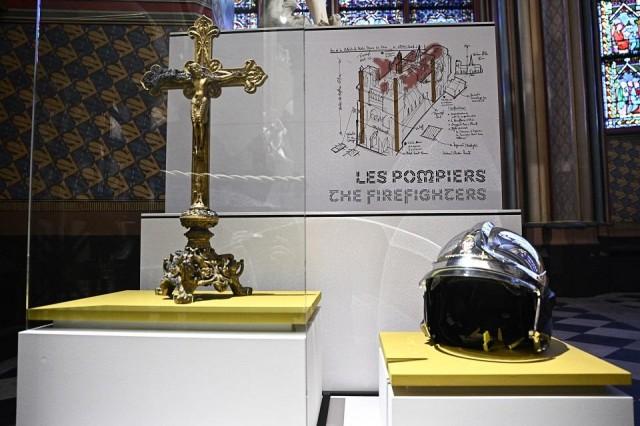 A sketch of the firefighters' intervention plan during the 2019 fire can be seen with a firefighter's helmet and a burnt cross on display at the Notre-Dame de Paris cathedral, in Paris on December 8, 2024. Julien de Rosa/ AFP