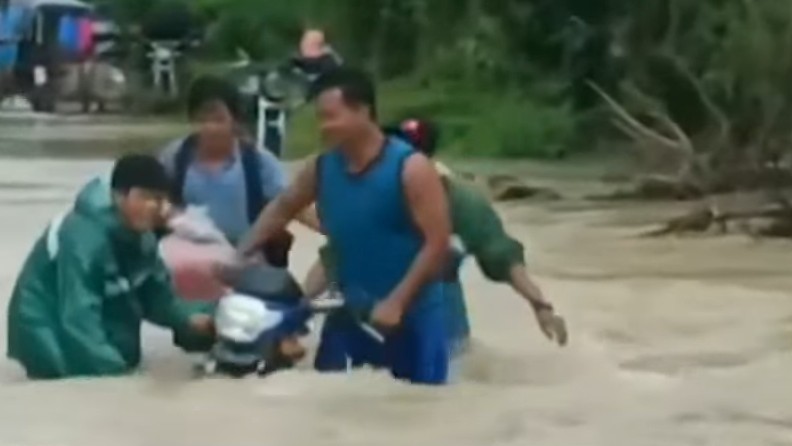 Residents attempt to help a motorist cross a flooded in Tagkawayan in Quezon province this week. 