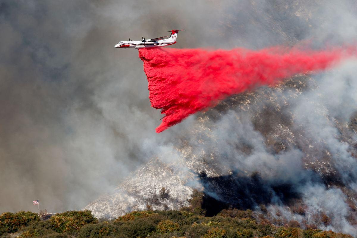 A plane makes a drop as smoke billows from the Palisades Fire at the Mandeville Canyon in Los Angeles, California