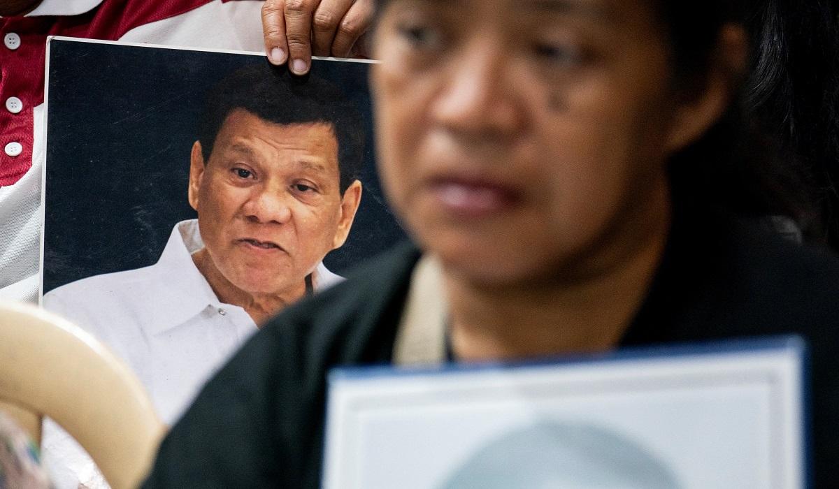 A picture of Duterte is held up by a drug war victim's loved one during a viewing of his appearance at the ICC