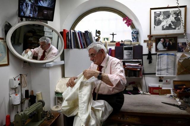 Clerical robe tailor Raniero Mancinelli works on a white papal cassock at his liturgical vestments shop near the Vatican, in Rome, Italy, April 29, 2025. REUTERS/ Guglielmo Mangiapane