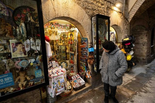 A woman passes by a shop selling souvenirs of Carlo Acutis, who died of leukemia in 2006 aged 15, in Assisi, Italy, April 10, 2025. Pope Francis has cleared the way for Acutis to be the first saint of the millennial generation. REUTERS/Remo Casilli