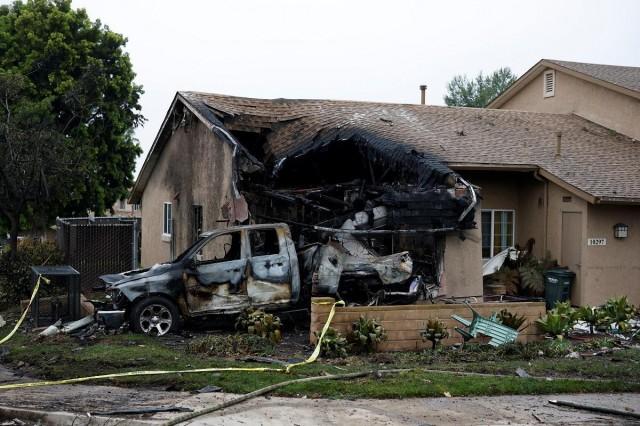 A view shows a damaged house and vehicle at the crash scene, after a small civilian aircraft went down in a military neighborhood in San Diego, California, May 22, 2025. REUTERS/ Mike Blake