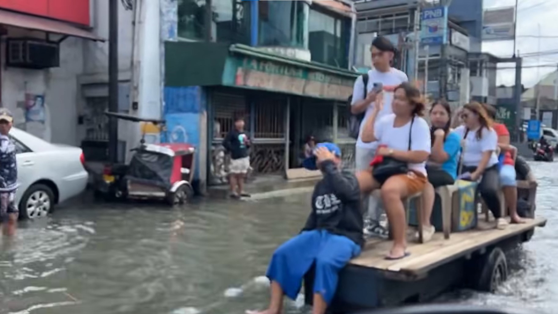 LOOK: Malabon residents ride wooden cart to cross flood