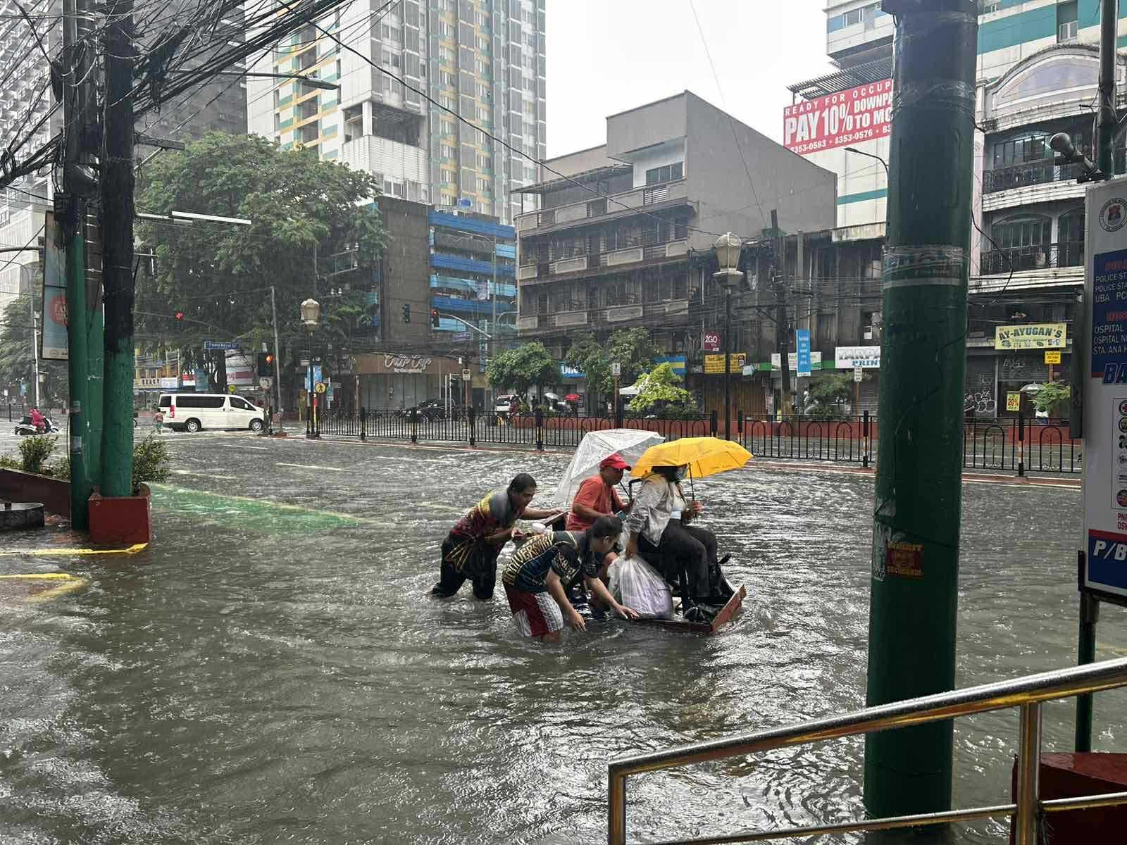 People navigate floodwaters along Espana Boulevard in Manila