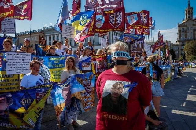 A woman wearing a blindfold with the word 'Silence!' and a T-shirt with an image of a missing Ukrainian serviceman stands next to missing servicemen's relatives holding flags, signs and banners during a rally, as the country celebrates Independence Day, amid Russia's attack on Ukraine, in the center of Kyiv, Ukraine, August 24, 2025. REUTERS/ Alina Smutko