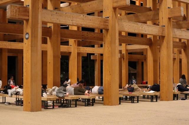 Visitors sleep outside under the Grand Ring overnight after a power outage abruptly shut down the Osaka Metro line linking the city to the 2025 Osaka Expo site, in Osaka early on August 14, 2025. Jiji Press/ AFP