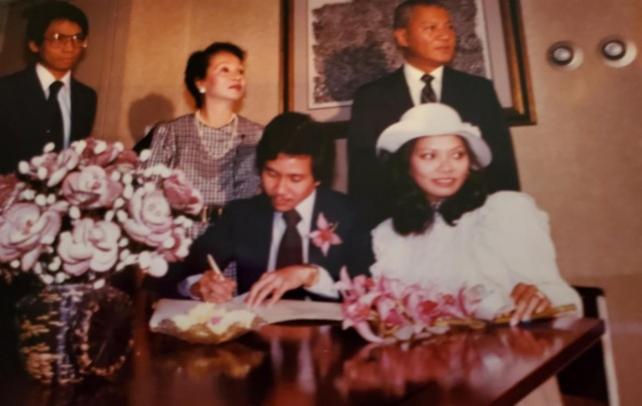  Bong signing the matrimonial certificate. Behind the couple are Consul General Pineda, his wife Vicky Pineda, and young diplomat Willy Gaa who would later become consul general in New York. Courtesy: Darlene Borromeo via The FilAm