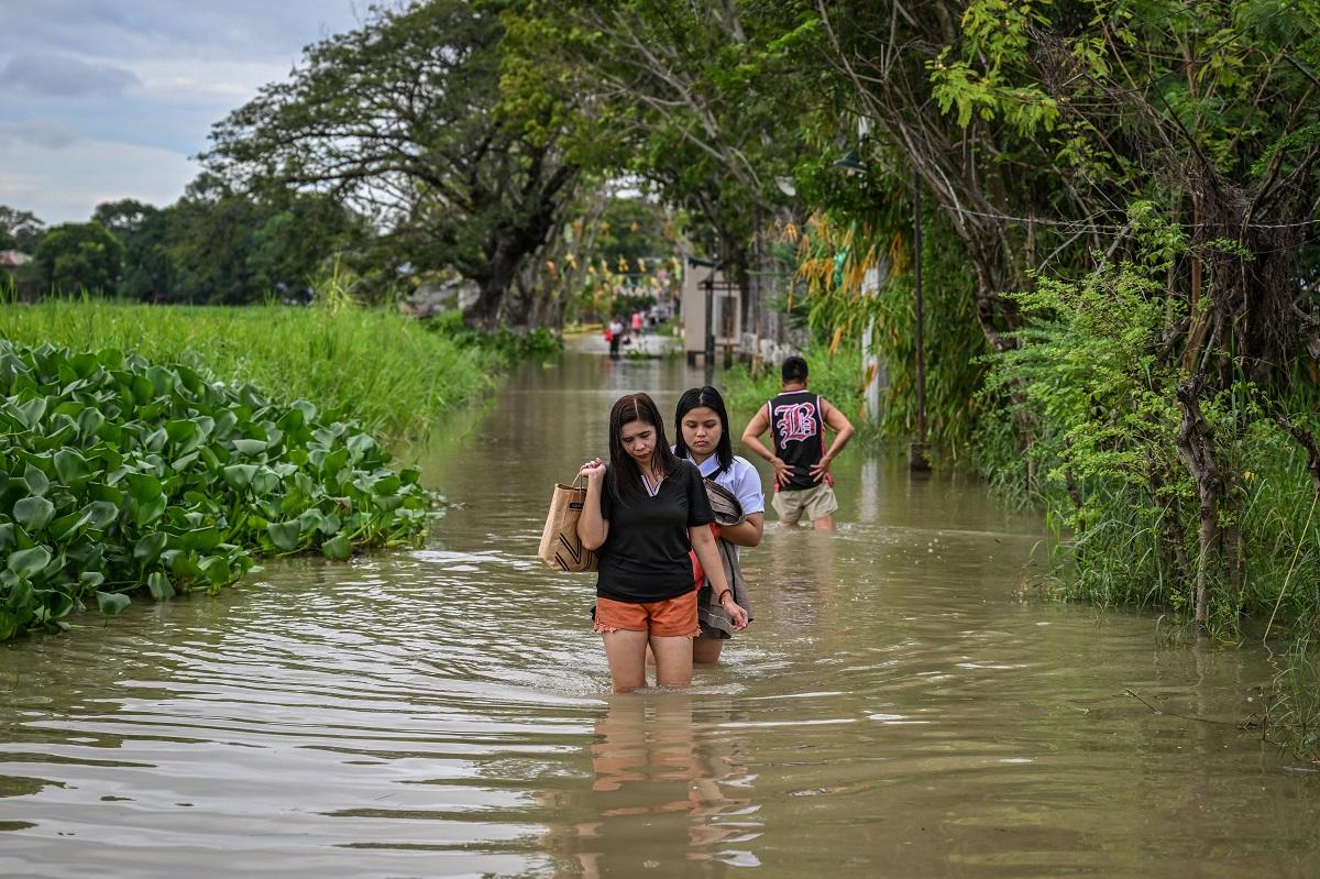 Residents wade through a flooded road in Calumpit, Bulacan