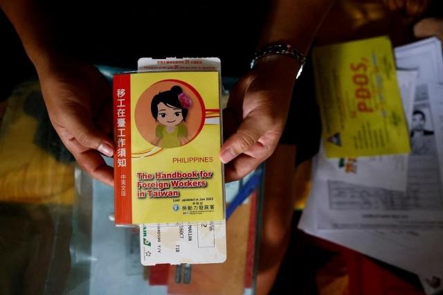 Marian Duhapa holds a handbook for foreign workers in Taiwan along with her flight ticket from her first trip abroad to Taiwan, in New Taipei City, Taiwan, July 18, 2024. REUTERS/ Ann Wang