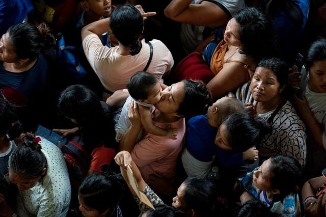 A woman kisses a child as they line up to register at an evacuation center as they prepare for Super Typhoon Uwan (Fung-Wong), in Manila, November 9, 2025. REUTERS/ Lisa Marie David