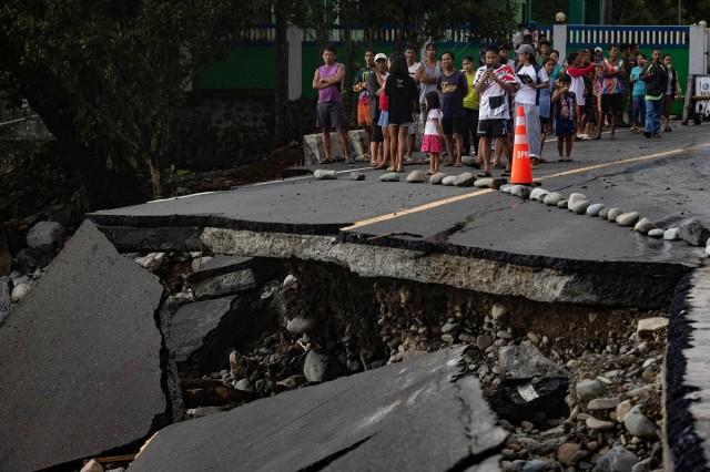 People stand near a wrecked part of the Baler-Casiguran road a day after Typhoon Uwan (Fung-wong) made landfall in Dipaculao, Aurora, November 10, 2025. REUTERS/ Eloisa Lopez