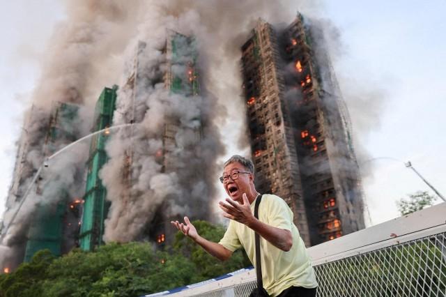 A man reacts, as smoke rises while flames engulf bamboo scaffolding across multiple buildings at Wang Fuk Court housing estate, in Tai Po, Hong Kong, China, November 26, 2025. REUTERS/ Tyrone Siu