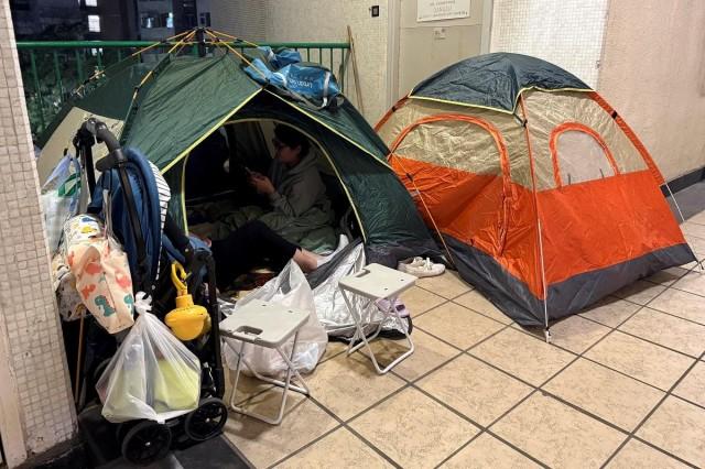 People sit in a tent at a mall, where many residents from a neighboring apartment had chosen to sleep for the night after being asked to evacuate following a deadly fire at the Wang Fuk Court housing complex, in Hong Kong, China November 27, 2025. REUTERS/ David Kirton