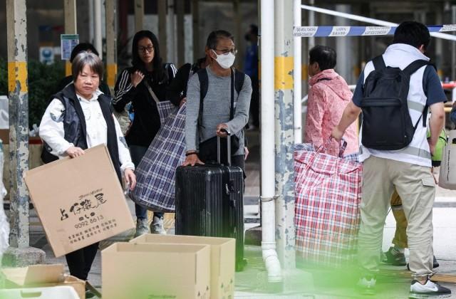 Residents of Wang Chi House, the only building not directly affected by the deadly fire at Wang Fuk Court housing complex, carry bags and suitcases after fetching their belongings, in Tai Po, Hong Kong, China December 3, 2025. REUTERS/ Maxim Shemetov