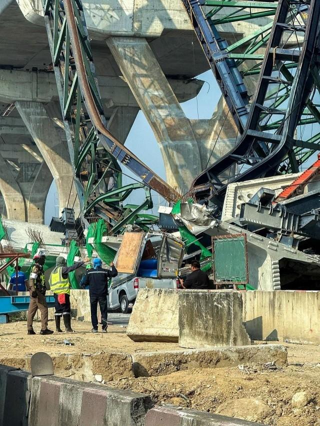 A police officer and workers stand next to a collapsed crane that crushed two vehicles during construction of an elevated highway in Samut Sakhon province, Thailand, January 15, 2026. Thai Rescue Worker Association/ Handout via REUTERS