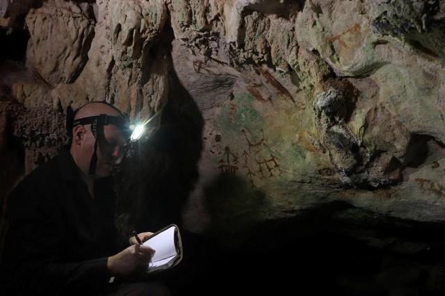 Researcher Maxime Aubert examines an ancient cave painting in Liang Metanduno cave, in this photograph released on January 21, 2026. Ahdi Agus Oktaviana/ Handout via REUTERS