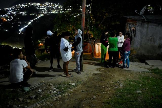 Residents stand in front of their homes in the Gramoven neighborhood, as US President Donald Trump said on Saturday the US has struck Venezuela and captured its President Nicolas Maduro, in Caracas, Venezuela, January 3, 2026. REUTERS/Maxwell Briceno