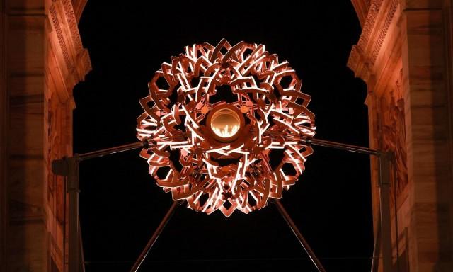 The Olympic flame can be seen in the cauldron during late evening, Arco della Pace, Milan, Italy, February 12, 2026. REUTERS/ Fabrizio Bensch