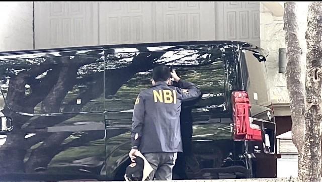 A National Bureau of Investigation (NBI) agent uses a flashlight to look inside a parked vehicle as other operatives scour a residential compound in Makati City to look for businessman Charlie 'Atong' Ang on Thursday, February 12, 2026. JOHN CONSULTA/ GMA Integrated News