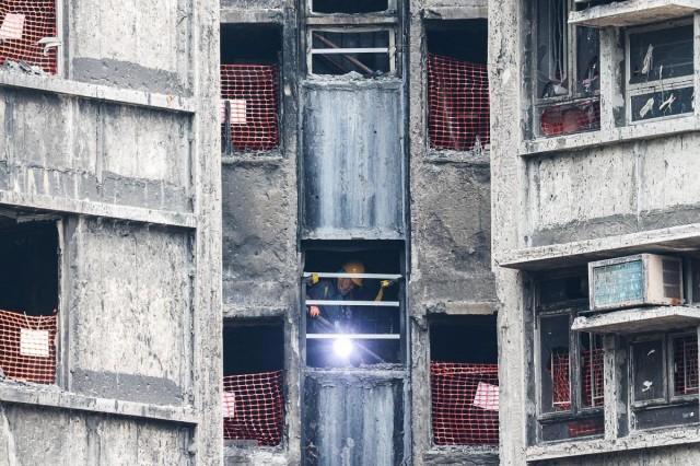 A resident carries belongings down the stairs after retrieving personal items from her flat at Wang Fuk Court during her first visit following a deadly fire last year, in Hong Kong, China, April 20, 2026. REUTERS/ Tyrone Siu