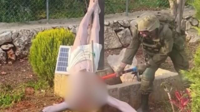 A member of the Israel Defense Forces (IDF) smashes a crucifix in the garden of a home in southern Lebanon, in this photo posted online by Palestinian journalist Younis Tirawi. Reuters video