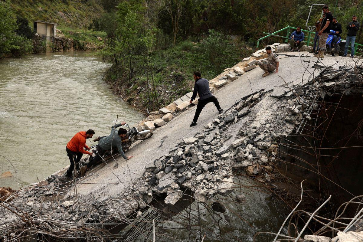 People cross a damaged bridge in Lebanon hit by Israeli air strike