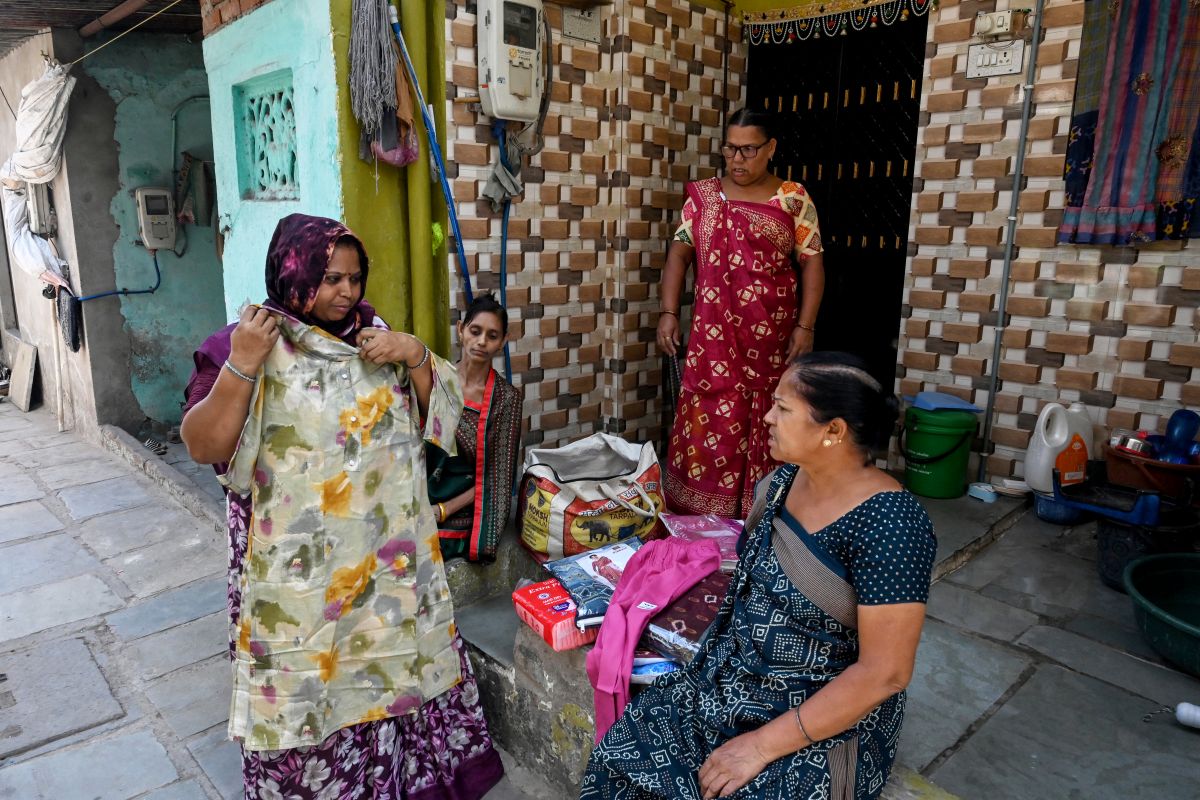 Lata Solanki (L), a clothes seller and policyholder of a heat insurance scheme, conducts door-to-door sales in Ahmedabad.