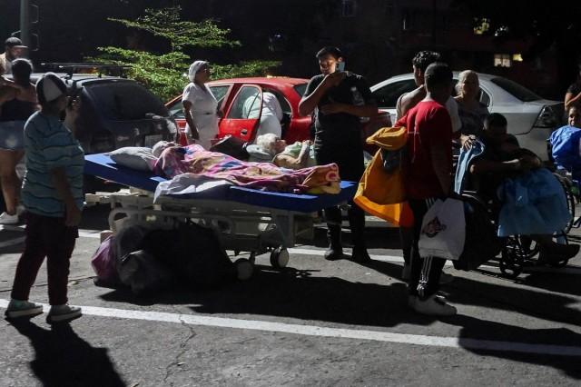 People stand next to patients in wheelchairs and hospital beds on the street outside a hospital after the earthquakes, in Caracas, Venezuela, June 24, 2026. REUTERS/ Leonardo Fernandez Viloria