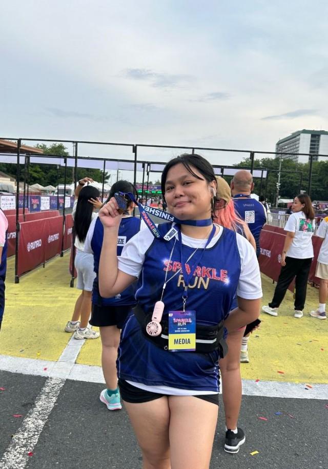 The author proudly displaying her medal after finishing the 5km-run with a sprained ankle