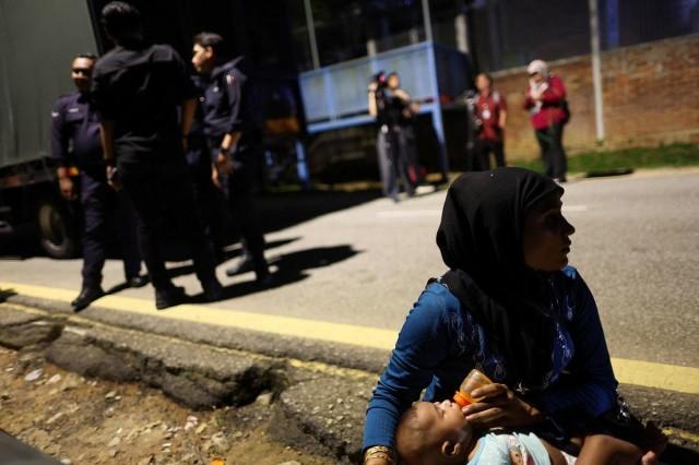 A Rohingya refugee feeds a child, as they gather in front of the office of the UNHCR after being evicted from their homes, in Kuala Lumpur Malaysia July 27, 2026. REUTERS/ Hasnoor Hussain