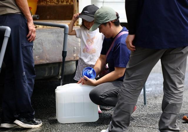 Yuka Shimada and daughter Tsugumi receive water aid due to a water supply outage, July 30, 2026. REUTERS/ Issei Kato