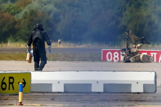 A police officer in protective clothing walks next to an explosive-disarming robot (EOD) at Leipzig/Halle Airport in Schkeuditz, Germany, August 5, 2026, after the police said explosives experts examined a drone found near a runway, and after a DHL cargo aircraft hit an unknown object as it was climbing away from the airport overnight, prompting an unscheduled landing in Hanover, according to a source familiar with the incident. REUTERS/ Axel Schmidt 