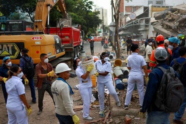 Nurses Lizeth Diaz, 35, Melissa Valenzuela, 30, and Anyie Velazco, 32, who work at the hospital opposite to the collapsed building, work to clear the rubble, after they volunteered to help following their 9-hour shift, amid parts of a destroyed structure following an earthquake, in Cali, Colombia, August 12, 2026. REUTERS/ Raquel Cunha
