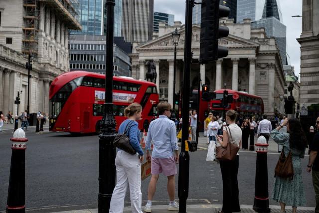 A worker wearing shorts crosses the road in the City of London during hot weather in London, Britain, August 17, 2026. REUTERS/ Chris J. Ratcliffe