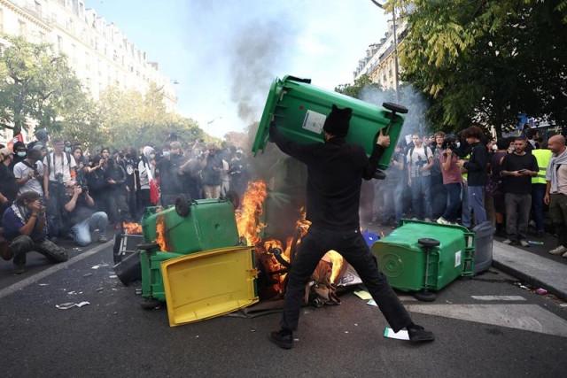 A protester throws a garbage bin into burning objects during a demonstration by high school and university students, supported by teachers' union and school parents, in Paris, France, October 6, 2026. REUTERS/ Abdul Saboor
