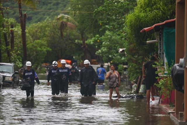 Marines wade through a flooded street as Hurricane Simon approaches Mexico's Pacific coast, bringing heavy rain and strong winds to Manzanillo, Mexico, October 11, 2026. REUTERS/ Daniel Becerril
