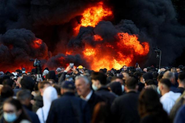 People gather near a fire as plumes of black smoke rise, amid an anti-government protest by students, in Tirana, Albania, October 14, 2026. REUTERS/ Florion Goga